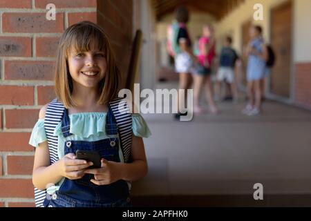 Schoolgirl leaning against a wall in the schoolyard at elementary school Stock Photo