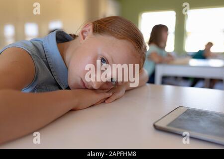 Schoolgirl leaning on her desk in an elementary school classroom Stock Photo