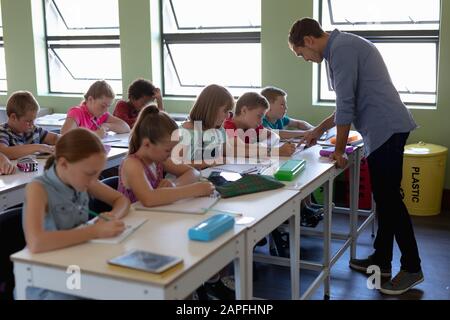 Group of schoolchildren sitting at desks working in an elementary ...