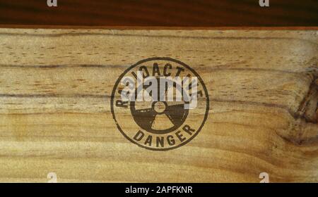 Radioactive danger symbol stamp printed on wooden box. Atomic energy warning, radiation alert and nuclear power hazard concept. Stock Photo