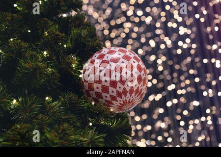 Christmas ball decoration hanging on festive xmas tree with bokeh out of focus background lights - Close up of decorative bauble ornament with copy space - seasonal, christmassy and holidays concept Stock Photo