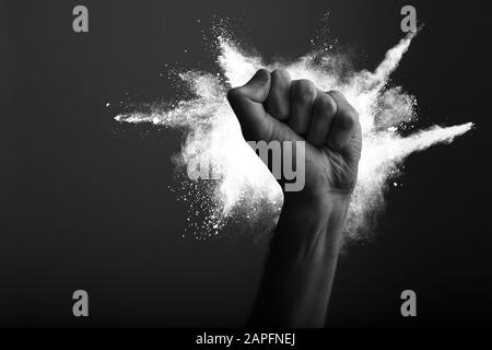 Raised clenched fist with white powder explosion, power, protest concept Stock Photo