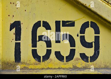 black-colored-number-one-thousand-six-hundred-fifty-nine-1659-on-a-yellow-rusty-metal-background-2apfrkx.jpg