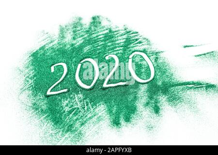 Inscription 2020 on a background of scattered green shiny sparkles on the white background. Stock Photo