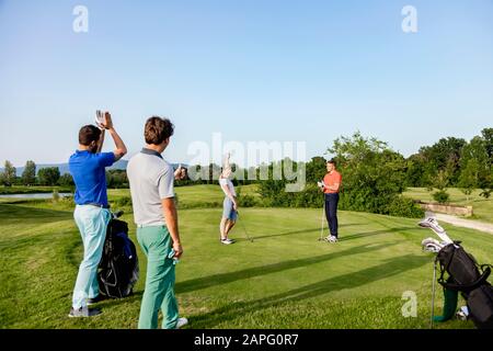 Friends playing golf on golf course Stock Photo