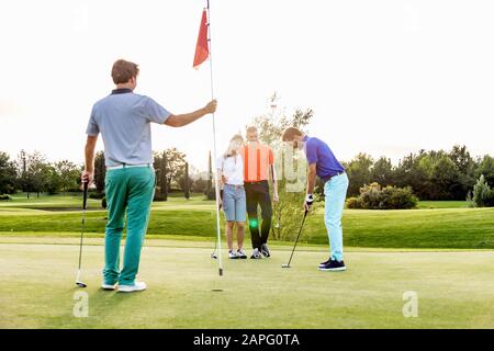 Friends playing golf on golf course Stock Photo