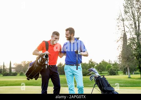 Friends talking and laughing on golf course Stock Photo