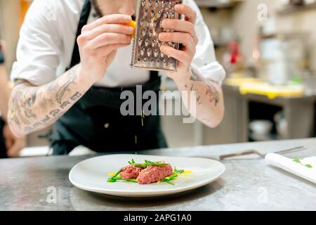 Chef preparing raw meat dish in kitchen Stock Photo