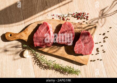 Thick slices of raw meat, rosemary, peppercorn Stock Photo