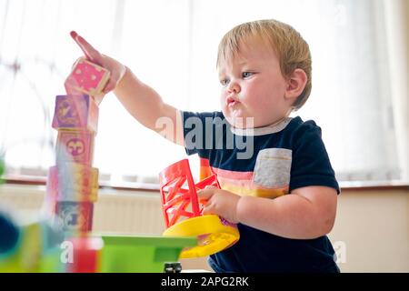 Toddler playing with building blocks in room Stock Photo