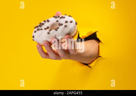 Hand holding a white donut with chocolate chips Stock Photo