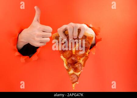 Hand holding a slice of pizza and showing a thumb up Stock Photo