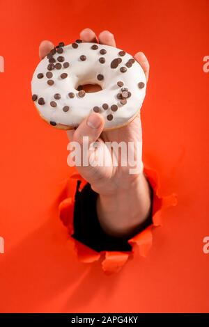 Hand showing a white doughnut with chocolate chips Stock Photo