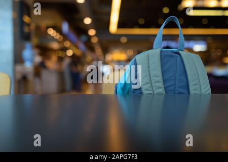 Close Up Portrait Of Blue Backpack Inside The Mall Against View Of Luminous Lights Stock Photo