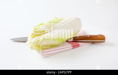Fresh Chinese cabbage and kitchen knife on dish towel Stock Photo