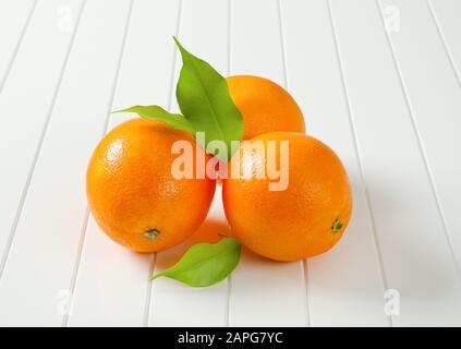 Three whole ripe oranges and leaves Stock Photo