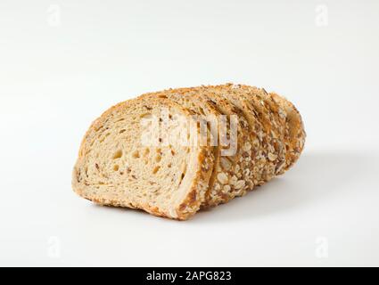 Sliced loaf of whole grain bread, crust topped with rolled oats and seeds (flax, sesame, sunflower) Stock Photo