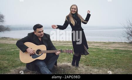 Man playing guitar while his partner is dancing Stock Photo