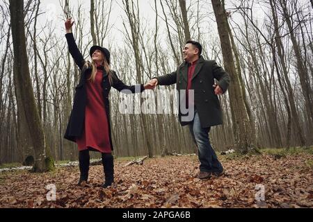 Happy couple enjoying a romantic walk in a forest Stock Photo
