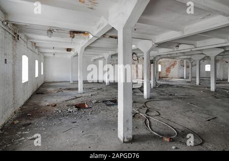 Empty industrial room of an old abandoned factory with white columns Stock Photo