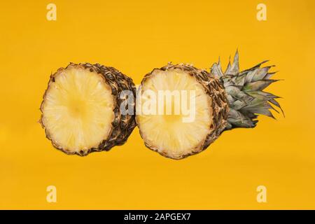 Pineapple half. Cut pineapple isolated on yellow. Pineapple with leaves. Stock Photo