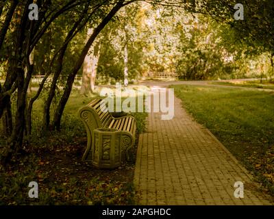 large bench on the path in the Park among the trees, autumn background, road Stock Photo