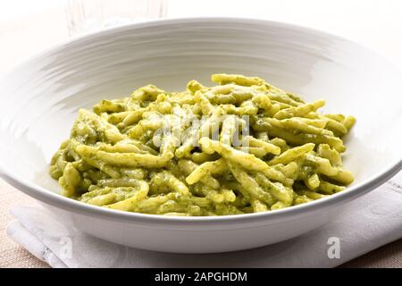 Trofie al pesto, a regional small twisted pasta strip with a pesto sauce, from the Liguria region of Italy in close up in a white bowl Stock Photo
