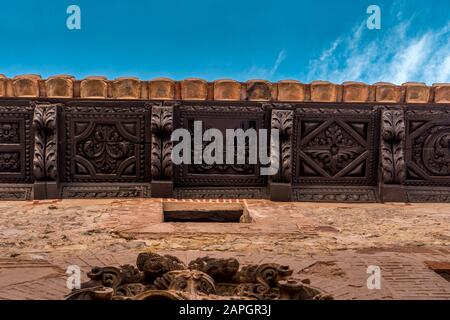 Medieval decorative wooden soffit with corbels and frieze on a house made of red terra cotta stone in Albarracin Spain against blue sky Stock Photo