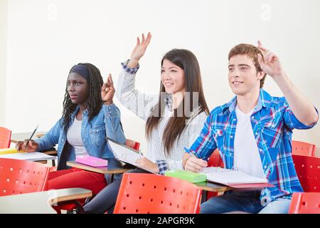 Three students at school raise their hands in class Stock Photo