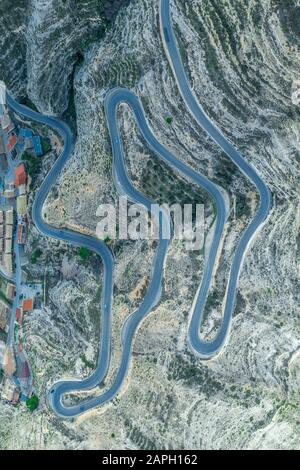 Aerial top down panorama view of a long serpentine curving road going up the hill from the bottom riverbed of the Jucar with dozens of sharp turns Stock Photo