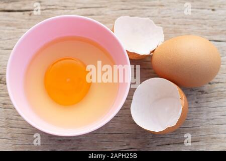 Broken egg shells and eggs on bowl, raw egg in small bowl at wooden background menu and recipe. Stock Photo