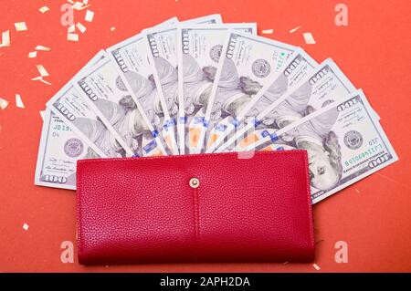 American US hundred dollar curency, banknotes in red wallet. Wealth, saving money, abundunce. Space for text on red background. Stock Photo