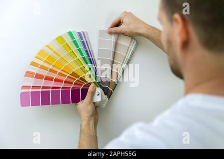 man selecting paint color from swatch for room wall Stock Photo