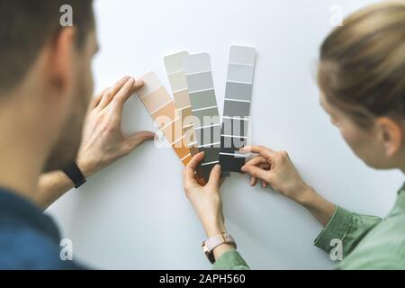 young couple choosing paint color from samples for new home interior design Stock Photo