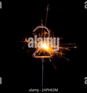 Burning sparkler in shape of number two, digit 2, isolated on black background. Stock Photo