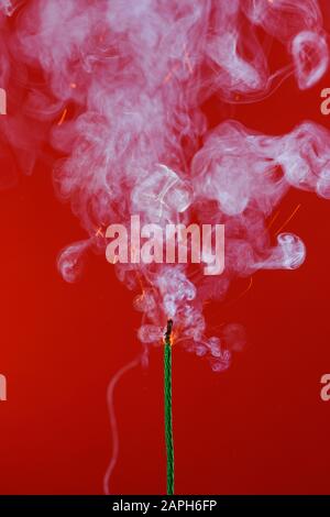 Burning fuse wick with sparks and smoke on red background Stock Photo