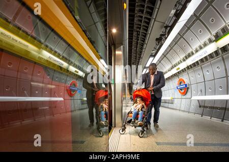 A man boards a Jubilee line train at Westminster with his buggy. Stock Photo