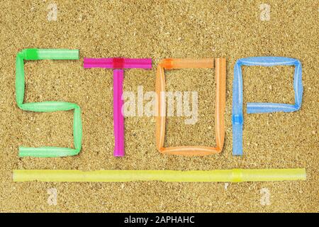 The word Stop written with plastic straws on beach sand - Concept of ecology and plastic pollution Stock Photo