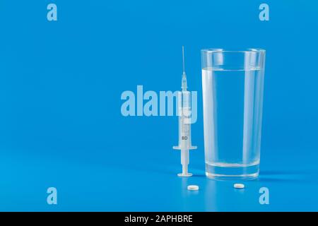 Glass with water and various pills isolated on blue background with copy space Stock Photo