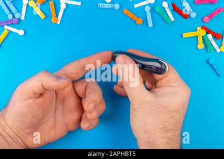 Diabetes test. Man hands checking blood sugar level by Glucose meter on blue background. A device for measuring blood sugar levels. Test strips, pills Stock Photo