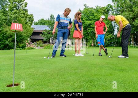 Golf players practising with golf pro on putting green Stock Photo