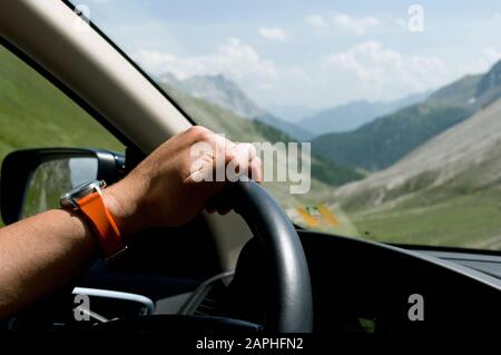Man hand holding on to the steering wheel of a car, Swiss Alps, Switzerland Stock Photo