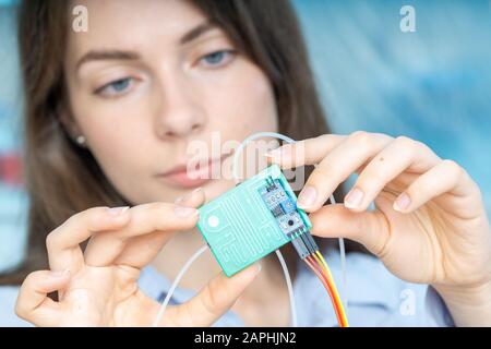Young scientist woman in microbiological lab with lab-on-chip LOC microfluidic device Stock Photo