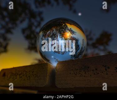 A sunset and a crescent moon in Everglades National park reflected in a lensball. Stock Photo
