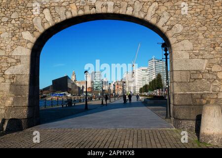 Looking through the granite stone gable and arch at the Royal Albert Dock towards Liverpool's waterfront buildings. Stock Photo