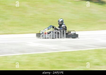 Florianopolis - Brazil, February 9, 2019: Dynamic image of pilot driving go-kart with motion blur effect, moving fast. kart competition on sunny day. Stock Photo