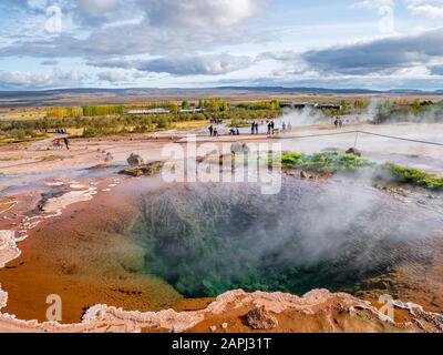 Blue pool with vapour in Haukadalur geothermal area with Strokkur big geyser steam in the background. One of the most visited and iconic sightseeings Stock Photo