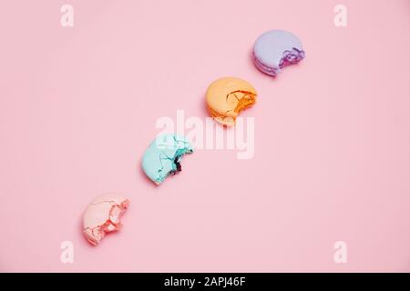 Minimalism, bitten macaroons on pink background, top view. Concept reducing interest rates on loans in banks, taxes Stock Photo