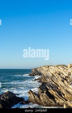 Ocean and Cliffs and a small lighthouse in the end of the cliffs. Stock Photo