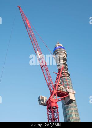 Red tower crane and Post Office Tower set against blue sky in Spring sunshine. Metaphor London construction activity, new builds, London sightseeing. Stock Photo
